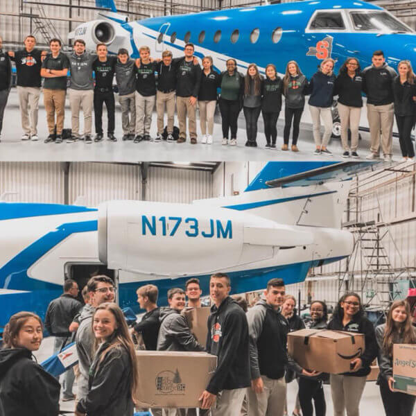 A group of students packing boxes in front of Adam Weitsman's private jet